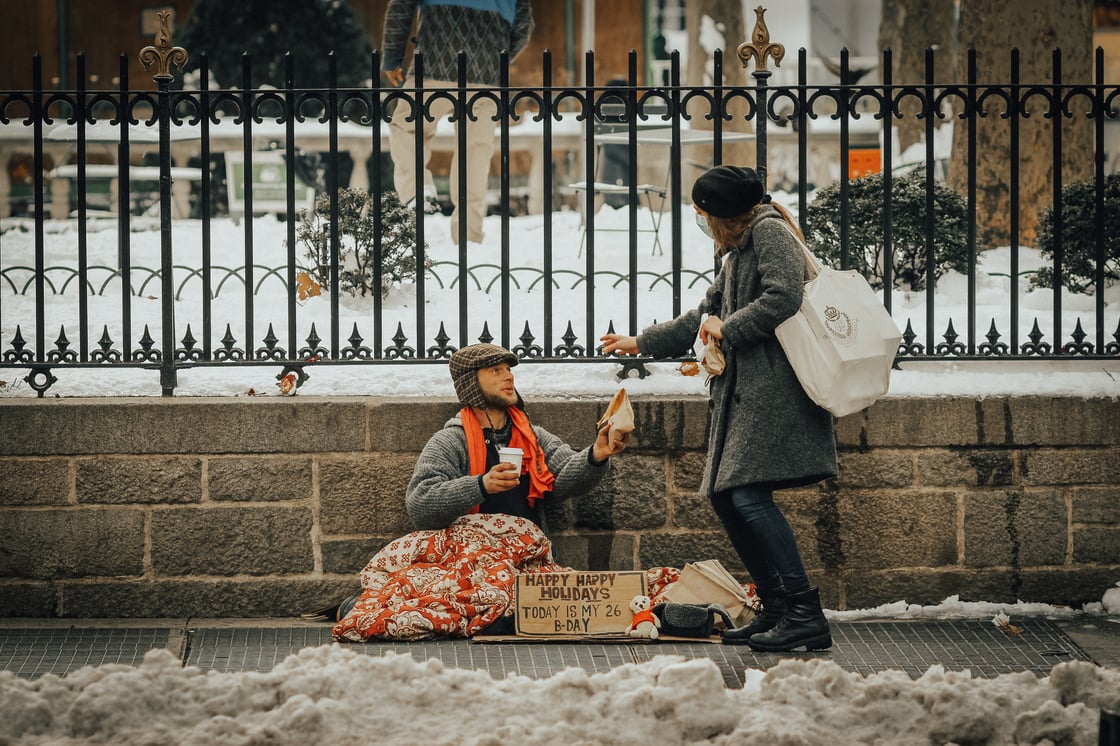 Woman giving money to homeless man